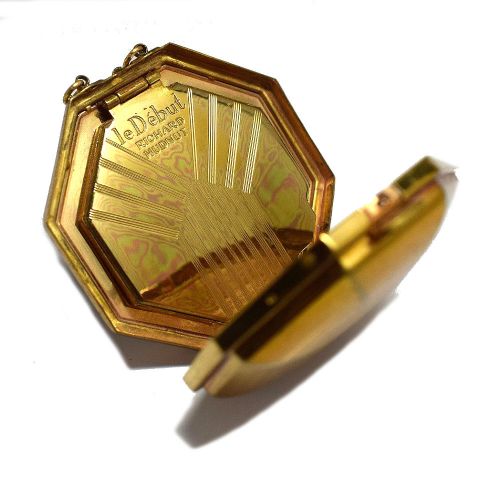 fig 2. An octagonal Art Deco powder compact by Richard Hudnut featuring black enamel, a central geometric motif, gold-tone trim, and an attached chain.