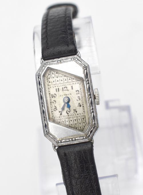 fig 1. An Art Deco ladies wristwatch featuring an octagonal engraved 14k white gold case, a patterned geometric dial, blue hands, and a black leather strap.