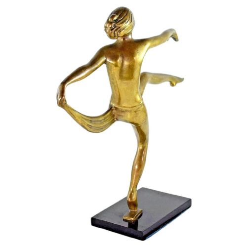 fig 1. A golden bronze Art Deco figurine depicting a nude female dancer poised in a dynamic pose on a dark rectangular wooden base.