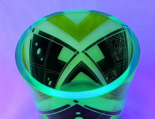 fig 1. A cylindrical green uranium glass vase featuring black enamelled geometric diamond patterns and etched foliate motifs.