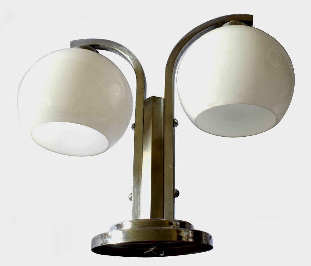 An Art Deco double table lamp featuring a chrome-plated stepped base, twin curved arms, and two white spherical glass shades. View IV