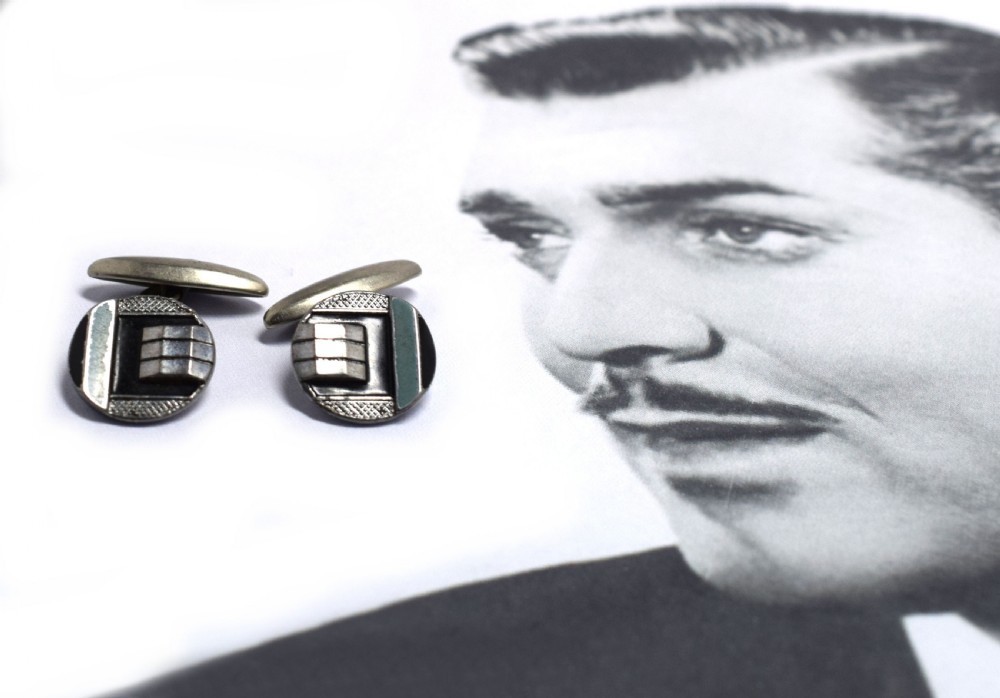 A pair of round Art Deco silver cufflinks decorated with black and light blue geometric enamel sections and raised stepped metal accents. View IV