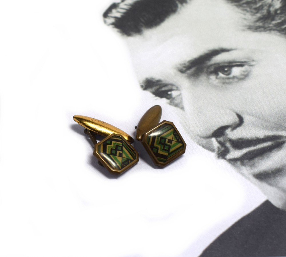 A pair of Art Deco gents cufflinks featuring octagonal faces inlaid with geometric green, black, and yellow enamel patterns framed in brass metal. View V