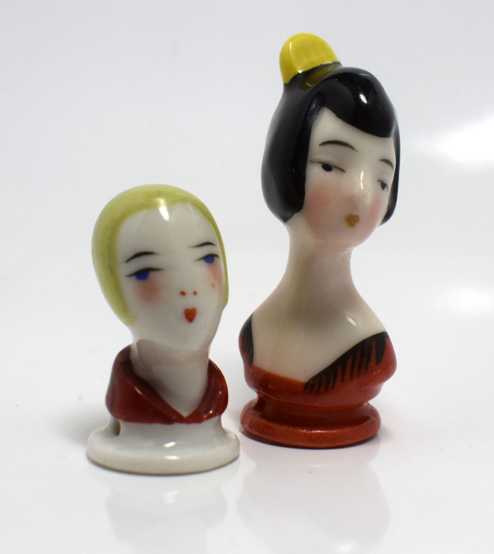 An Art Deco porcelain pincushion doll head featuring yellow bobbed hair, painted facial features, and a red collar. View V