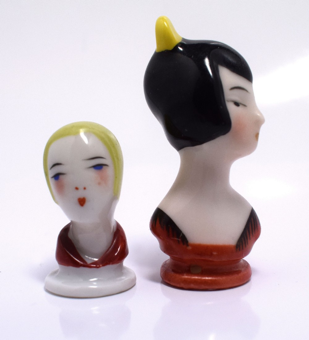 An Art Deco porcelain pincushion doll head featuring yellow bobbed hair, painted facial features, and a red collar. View VI