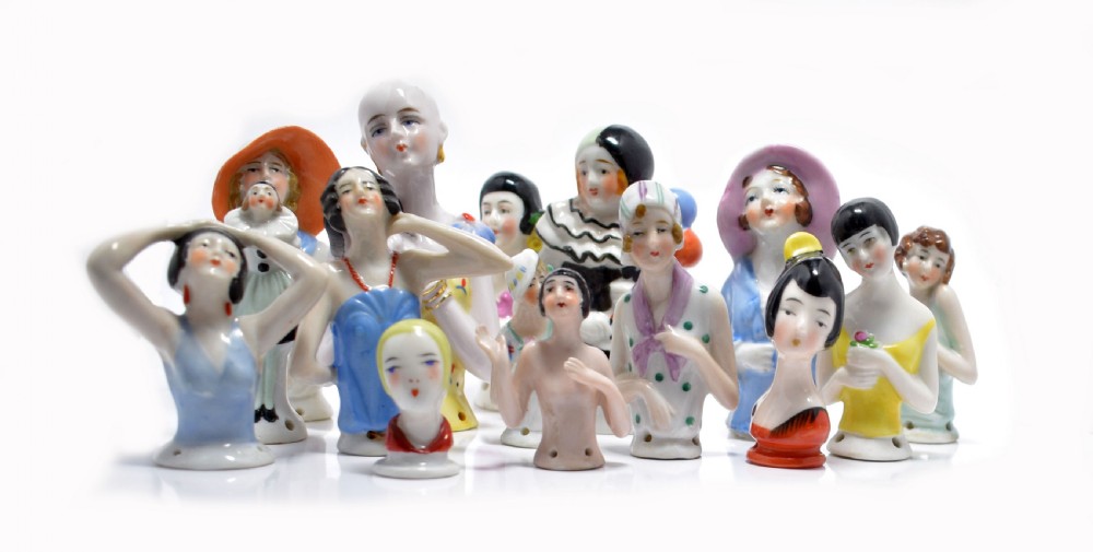 An Art Deco porcelain pincushion doll head featuring yellow bobbed hair, painted facial features, and a red collar. View VII