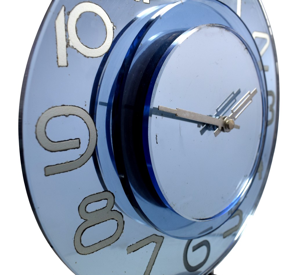 A circular Art Deco table clock made from blue mirrored glass featuring silvered numbers and a stepped circular glass base. View VI