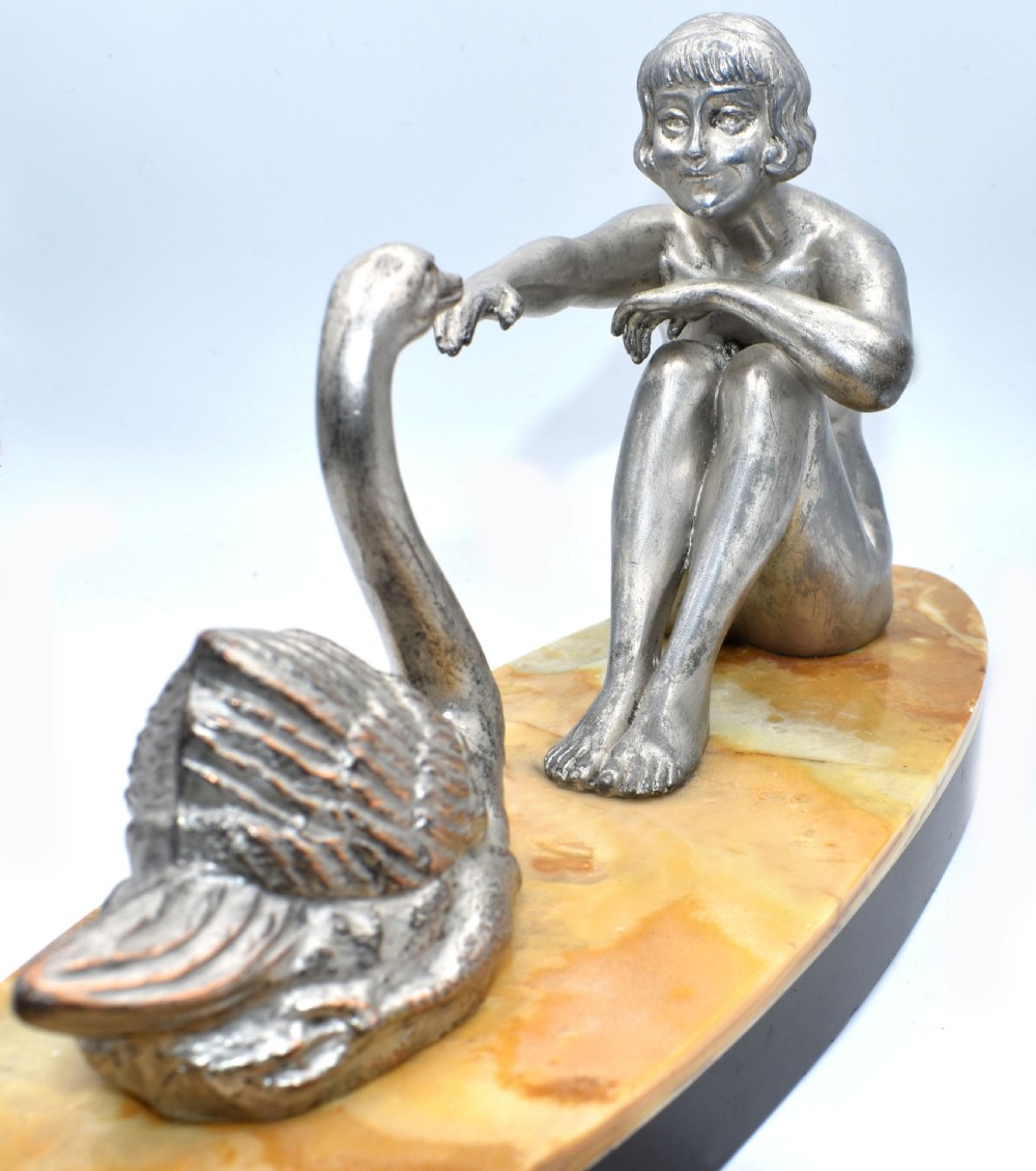 A silvered metal Art Deco sculpture featuring a seated female figure reaching towards a swan, mounted on a two-tone onyx and marble base. View II