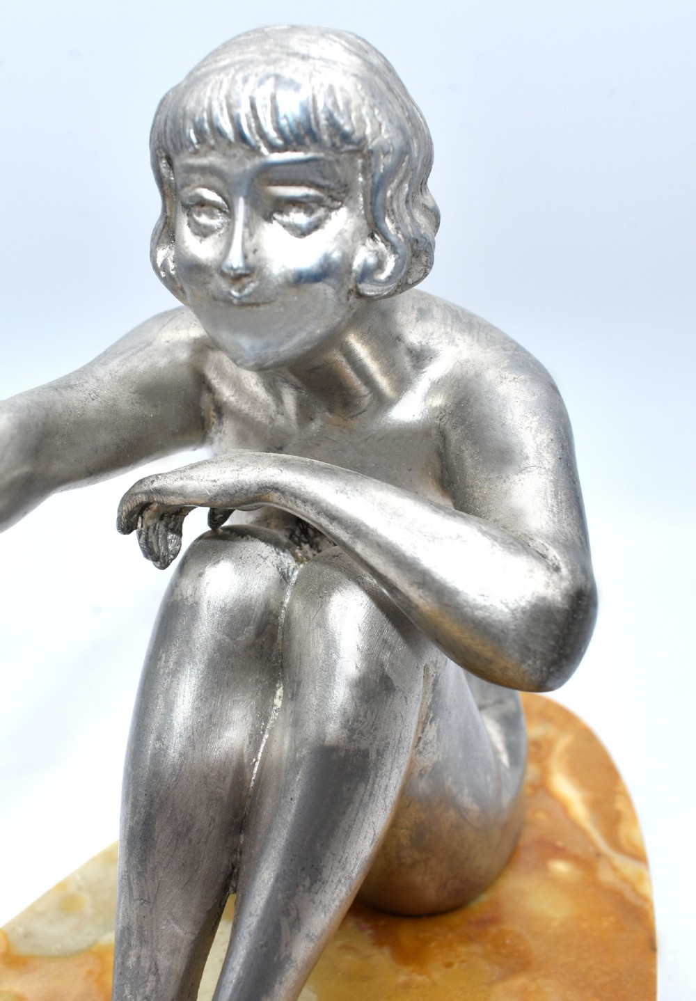 A silvered metal Art Deco sculpture featuring a seated female figure reaching towards a swan, mounted on a two-tone onyx and marble base. View III