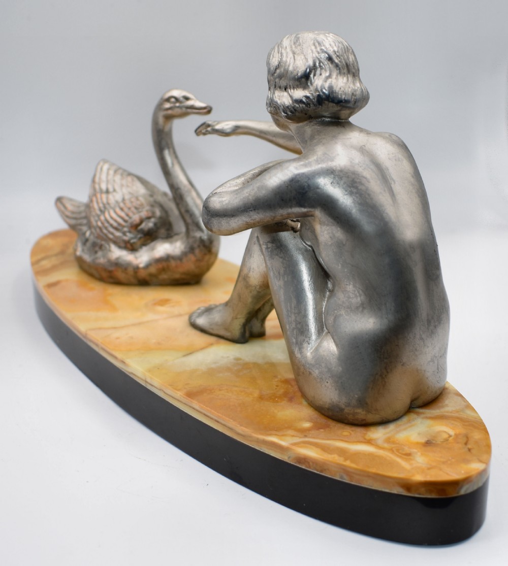A silvered metal Art Deco sculpture featuring a seated female figure reaching towards a swan, mounted on a two-tone onyx and marble base. View IV