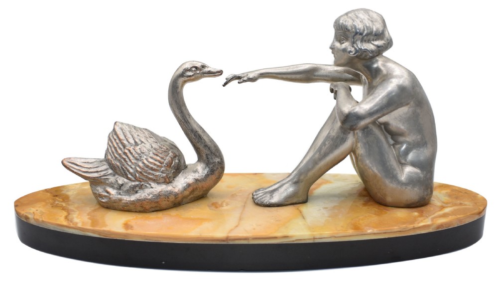 A silvered metal Art Deco sculpture featuring a seated female figure reaching towards a swan, mounted on a two-tone onyx and marble base. View VII
