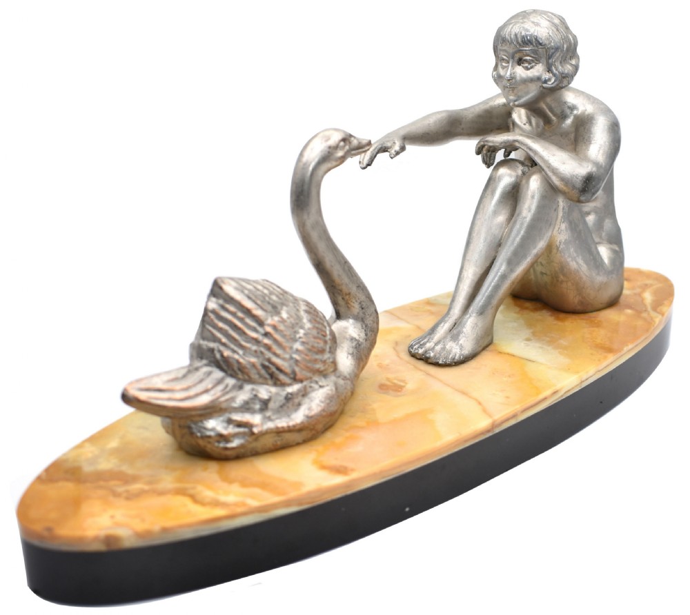 A silvered metal Art Deco sculpture featuring a seated female figure reaching towards a swan, mounted on a two-tone onyx and marble base. View VIII