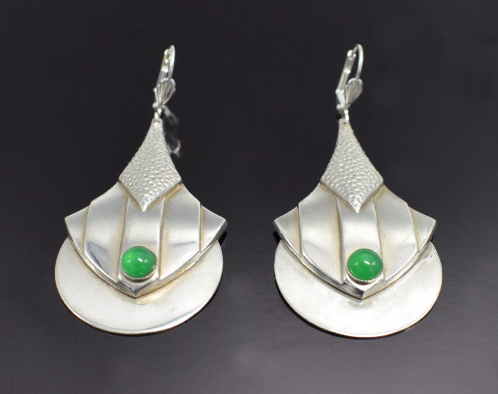 A pair of Art Deco style silver-plated drop earrings featuring geometric fan shapes, hammered detailing, and round green glass cabochons. View II