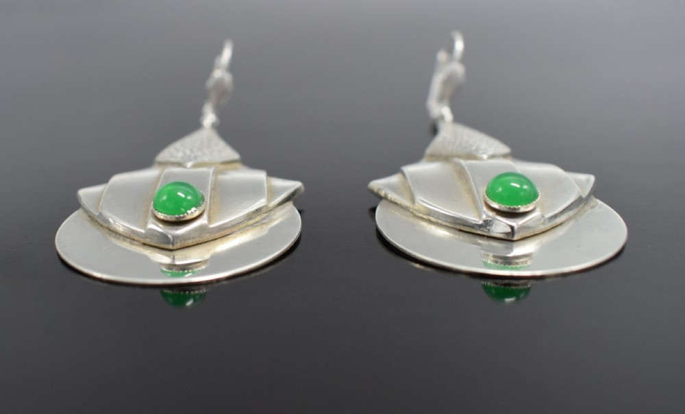 A pair of Art Deco style silver-plated drop earrings featuring geometric fan shapes, hammered detailing, and round green glass cabochons. View III