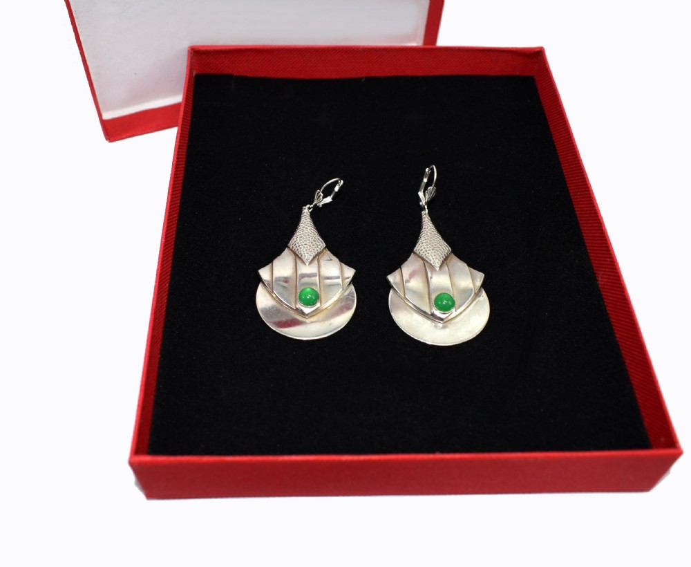 A pair of Art Deco style silver-plated drop earrings featuring geometric fan shapes, hammered detailing, and round green glass cabochons. View VIII