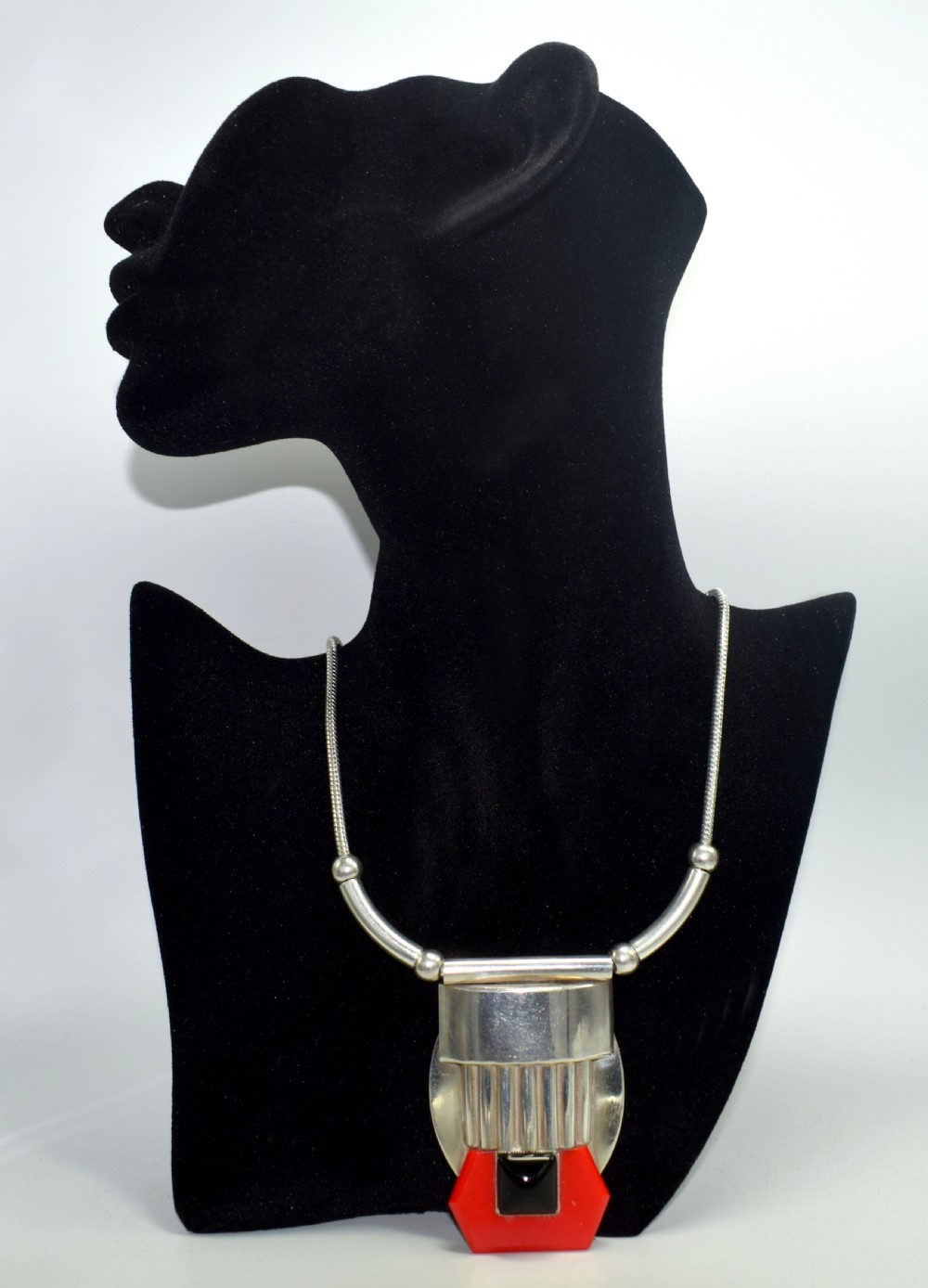 An Art Deco snake chain necklace featuring a geometric silver-tone pendant set with a red Galalith element and a central square black cabochon. View II