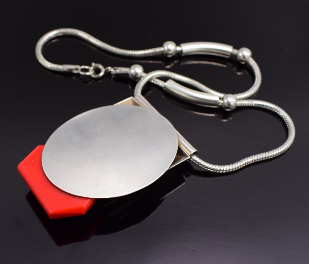 An Art Deco snake chain necklace featuring a geometric silver-tone pendant set with a red Galalith element and a central square black cabochon. View IX