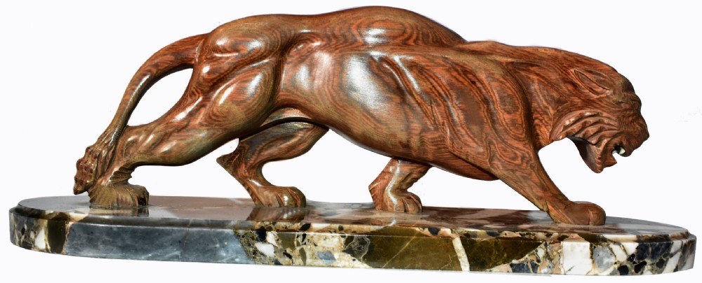 A stylised Art Deco sculpture of a prowling panther crafted from reddish-brown veined stone mounted on a variegated marble plinth.