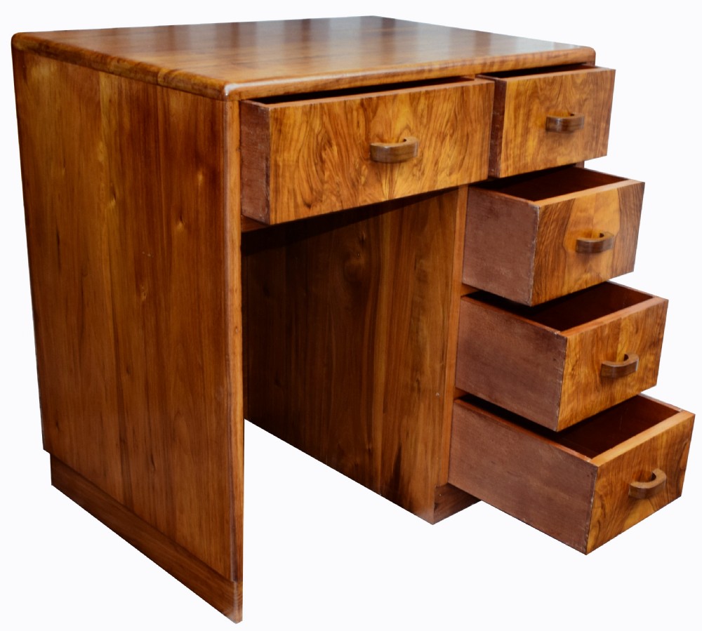 A 1930s Art Deco walnut writing desk featuring rounded corners, five drawers with wooden handles, and a kneehole section. View IX
