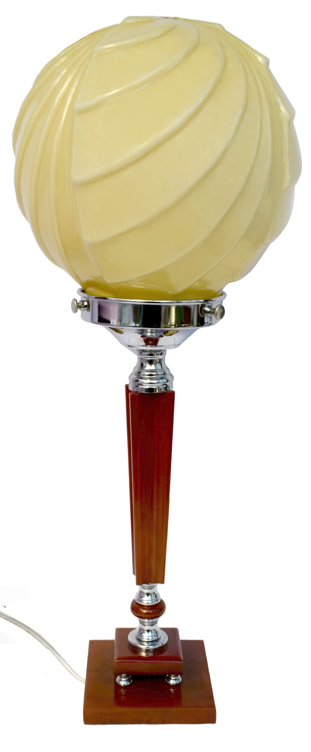 An Art Deco table lamp featuring a cream swirl glass globe shade set on a faceted amber Catalin resin and chrome stem base.