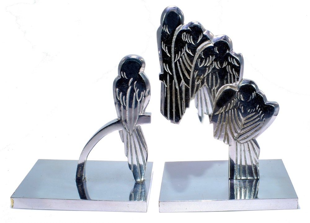 A pair of polished silver-coloured metal Art Deco bookends featuring stylised bird figures mounted on flat square bases. View V