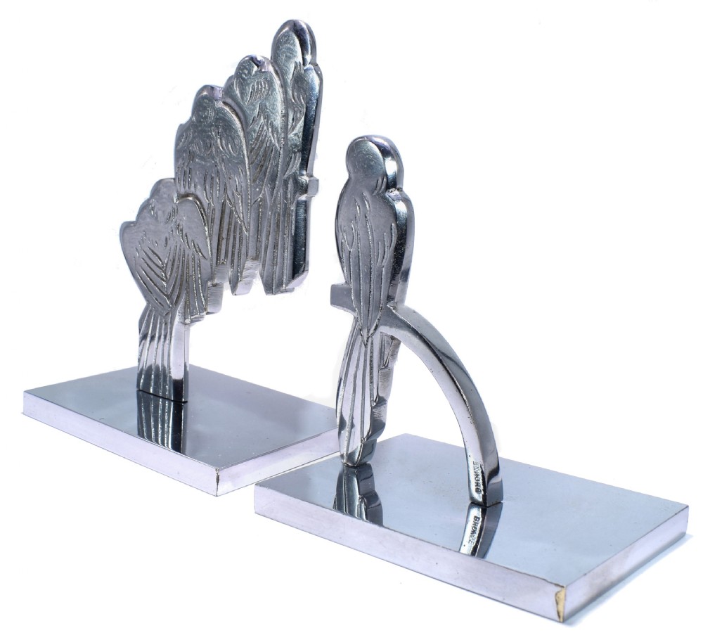 A pair of polished silver-coloured metal Art Deco bookends featuring stylised bird figures mounted on flat square bases. View VII
