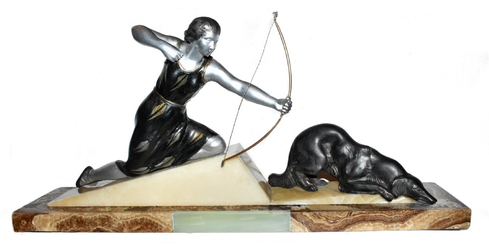 An Art Deco cold-painted metal sculpture depicting a female archer kneeling with a bow alongside a dog on a stepped onyx and marble base.
