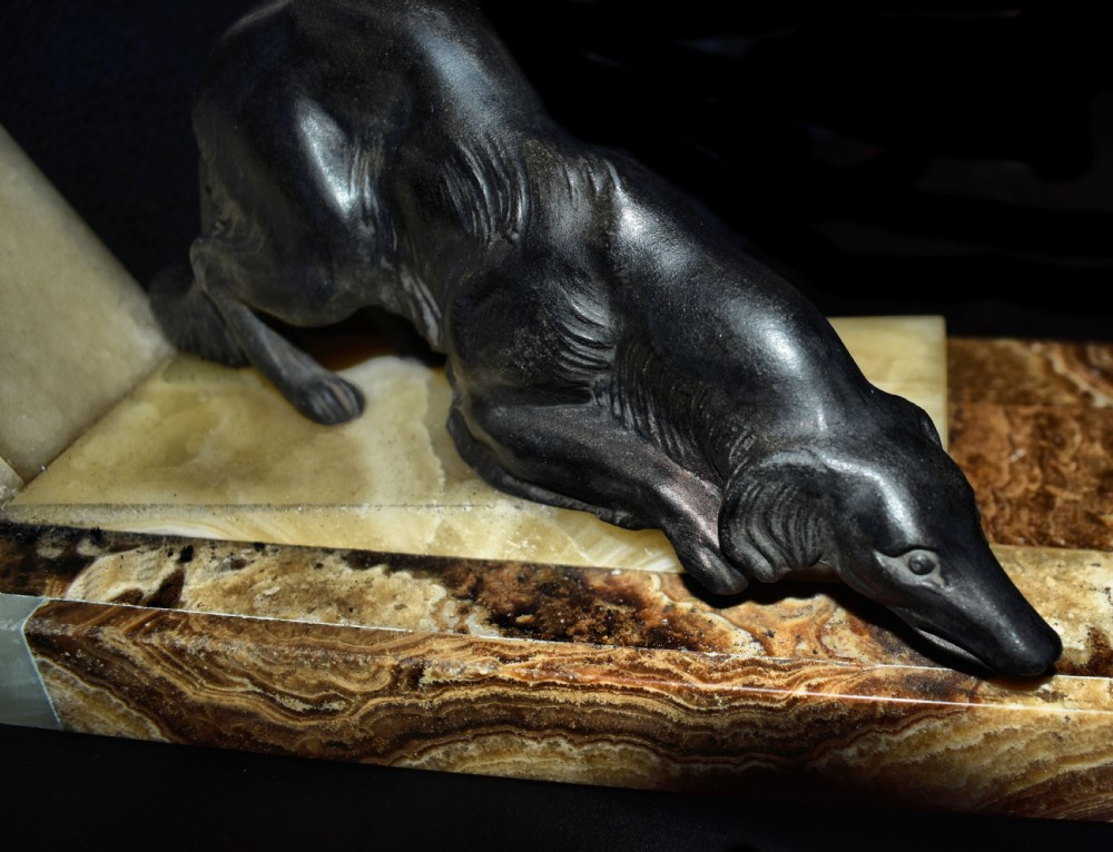 An Art Deco cold-painted metal sculpture depicting a female archer kneeling with a bow alongside a dog on a stepped onyx and marble base. View VI