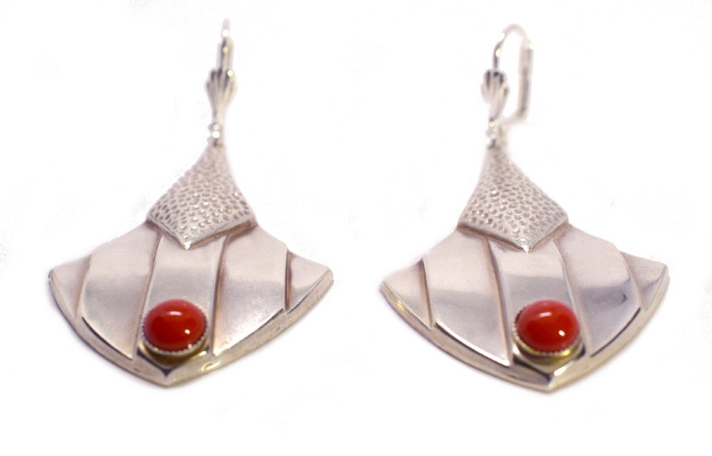 Pair of Art Deco silver drop earrings featuring stippled triangular upper sections, fan-shaped lower panels, and circular red cabochon stones. View V