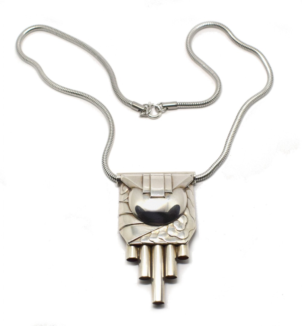 An Art Deco style silver-coloured chrome pendant featuring geometric stepped tubes and a central semicircle motif attached to a snake chain. View V
