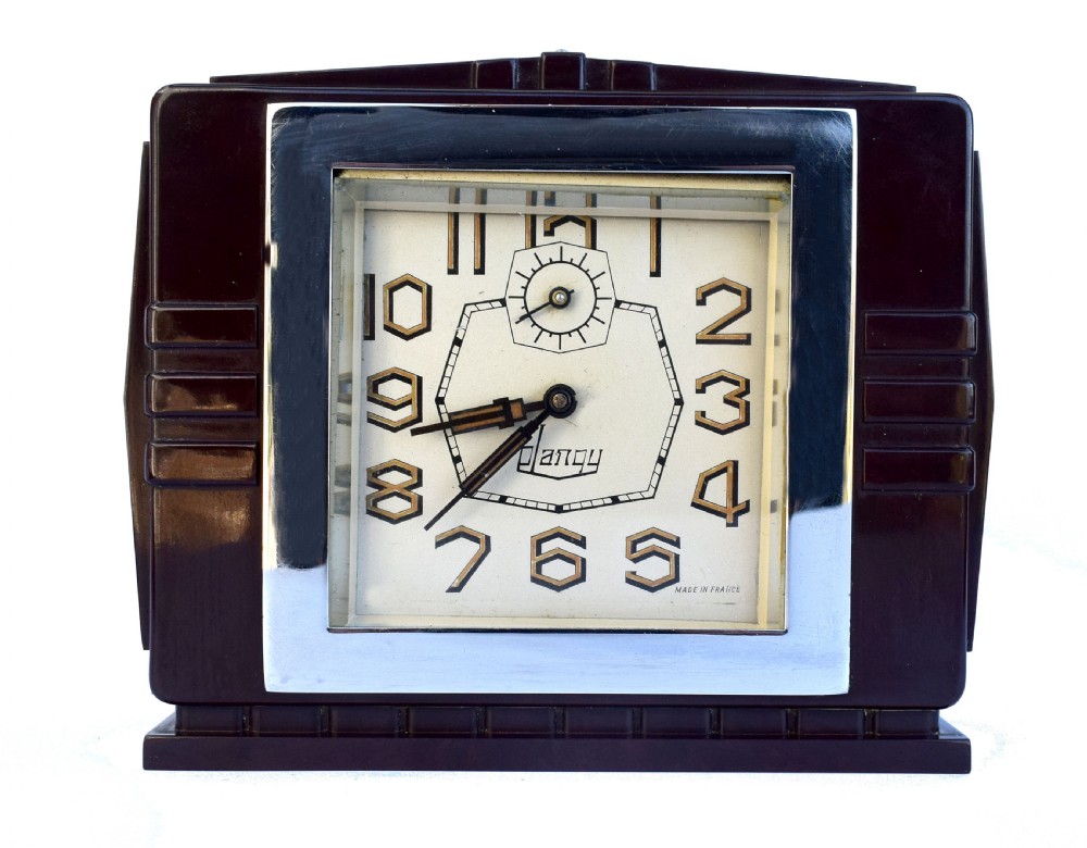 A square dark brown Bakelite mantel clock featuring stepped side details, a polished chrome inner frame, and a cream dial with Art Deco numeric typography.