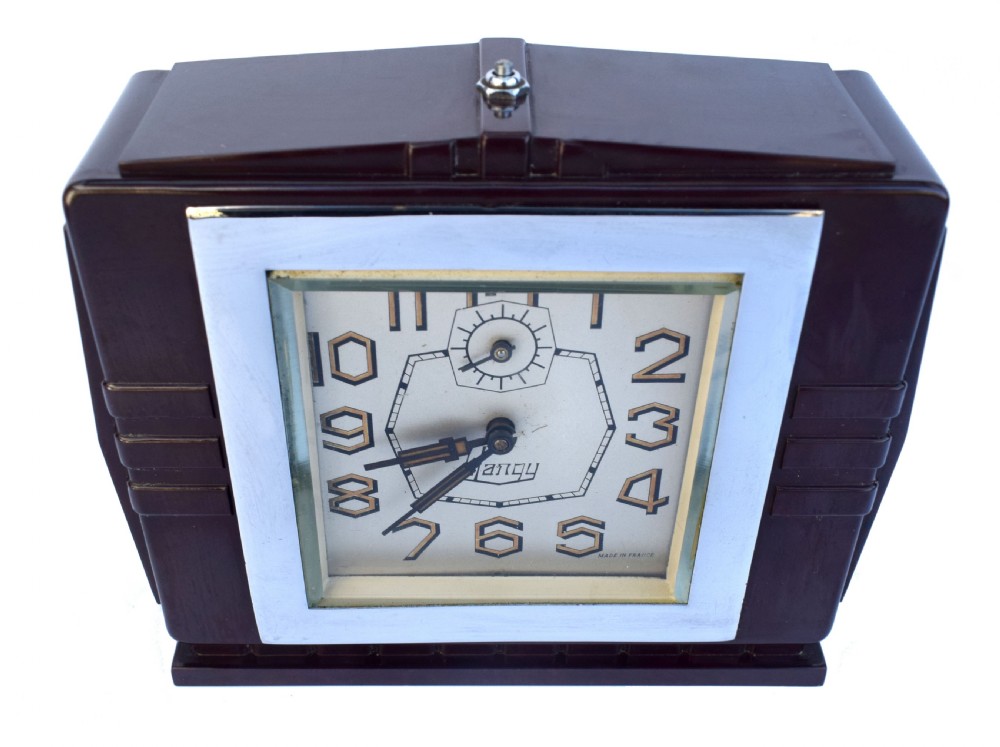 A square dark brown Bakelite mantel clock featuring stepped side details, a polished chrome inner frame, and a cream dial with Art Deco numeric typography. View II