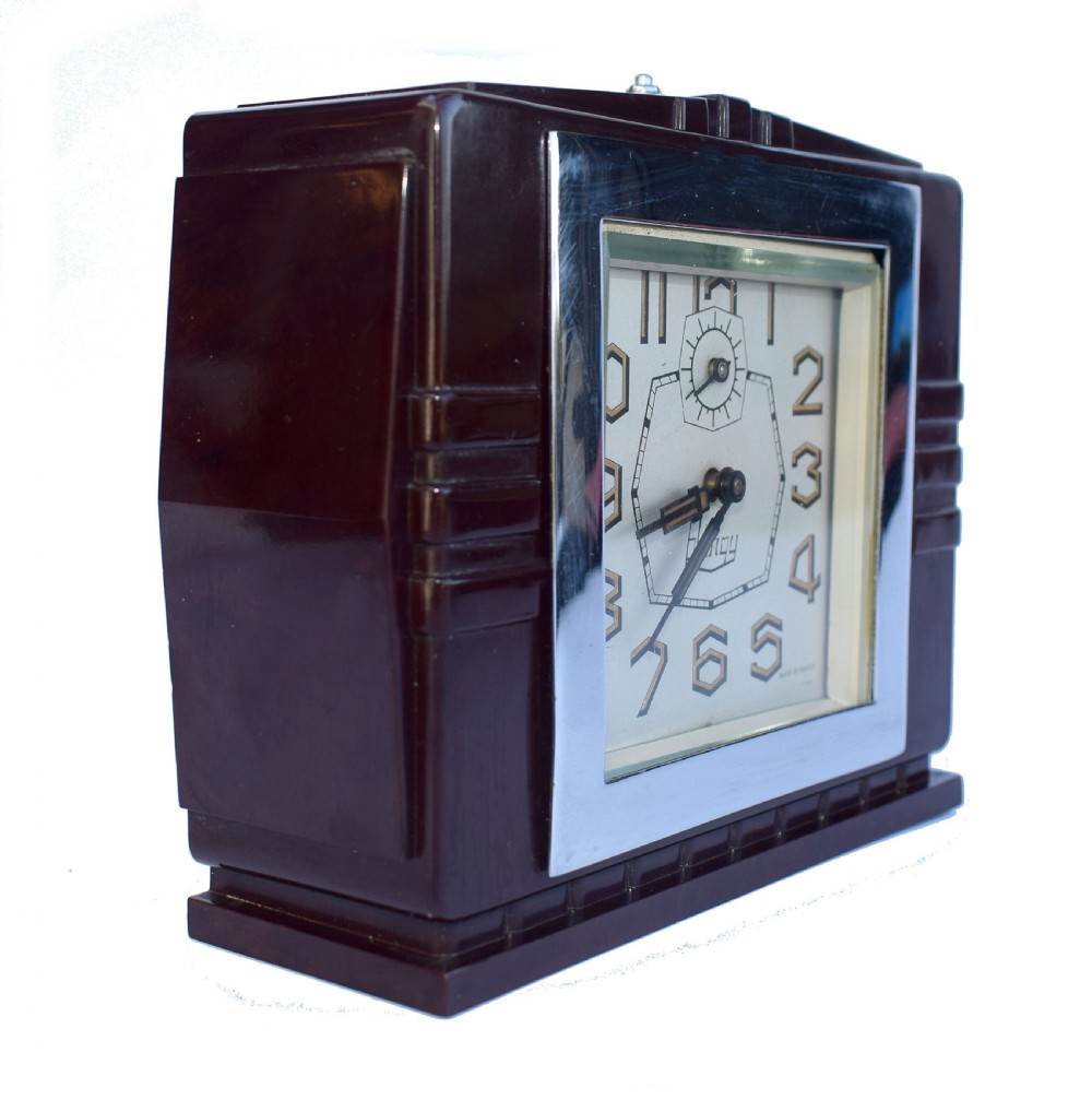 A square dark brown Bakelite mantel clock featuring stepped side details, a polished chrome inner frame, and a cream dial with Art Deco numeric typography. View III
