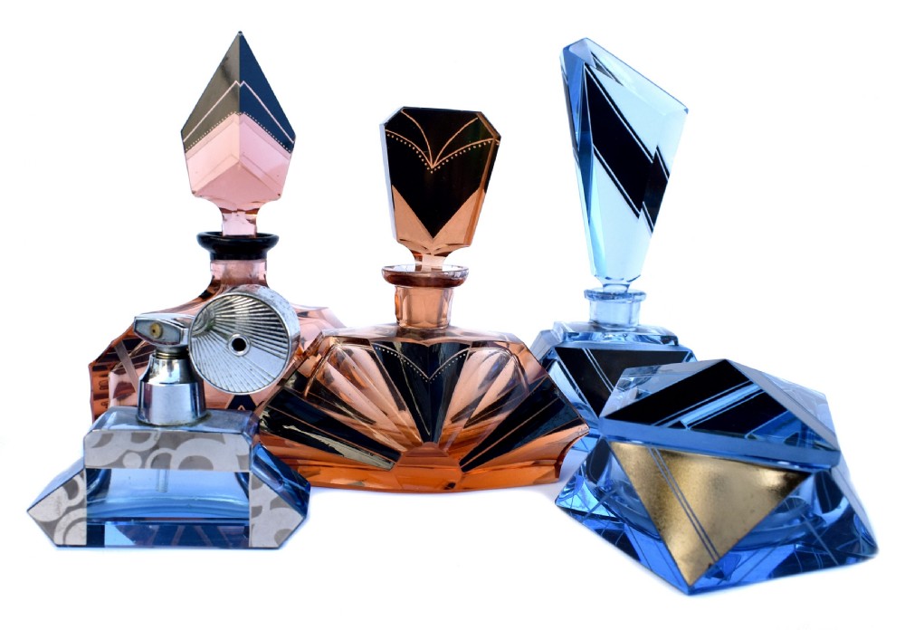 An Art Deco light blue glass vanity set consisting of a geometric scent bottle with a tall stopper and a matching powder box decorated with black triangular detailing. View VI