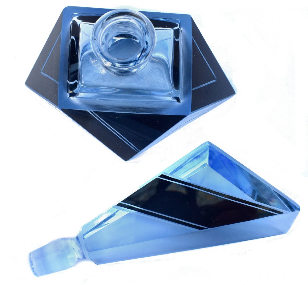 An Art Deco light blue glass vanity set consisting of a geometric scent bottle with a tall stopper and a matching powder box decorated with black triangular detailing. View VII
