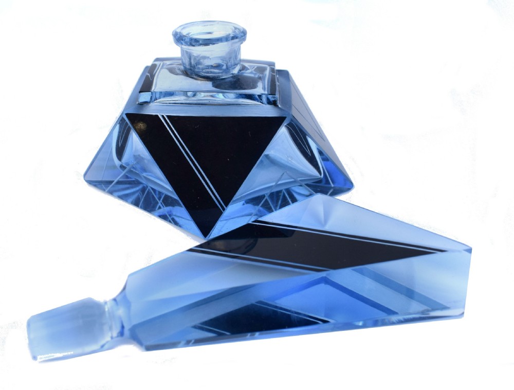 An Art Deco light blue glass vanity set consisting of a geometric scent bottle with a tall stopper and a matching powder box decorated with black triangular detailing. View VIII
