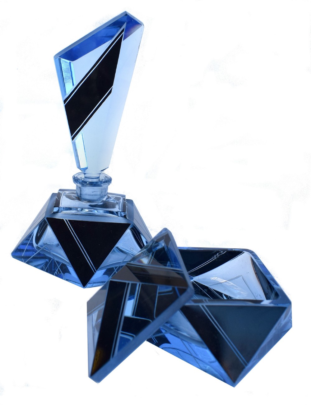 An Art Deco light blue glass vanity set consisting of a geometric scent bottle with a tall stopper and a matching powder box decorated with black triangular detailing. View IX