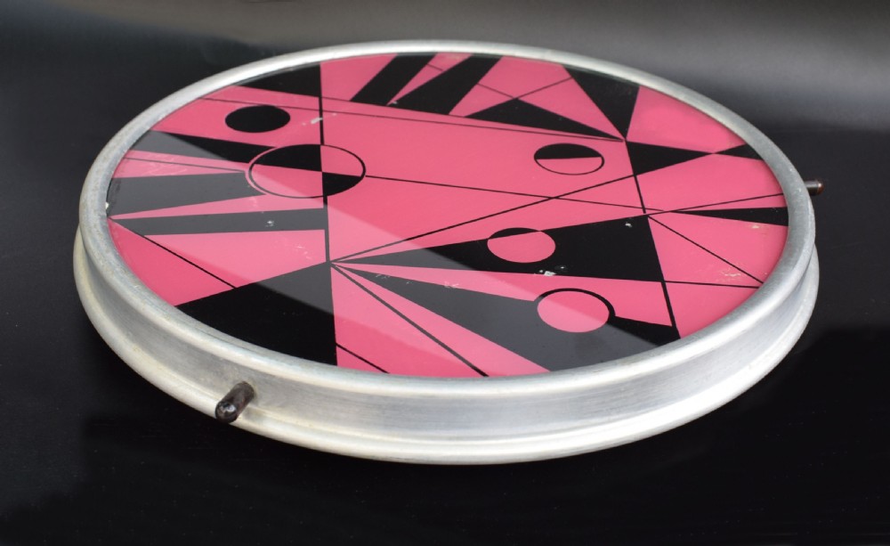 A circular Art Deco Lazy Susan featuring a pink and black abstract geometric pattern encased within a silver metal rim. View III