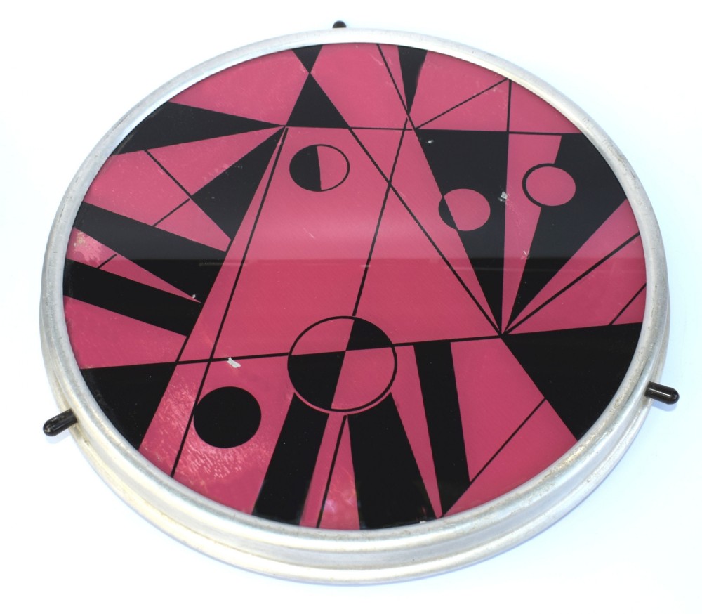 A circular Art Deco Lazy Susan featuring a pink and black abstract geometric pattern encased within a silver metal rim. View V