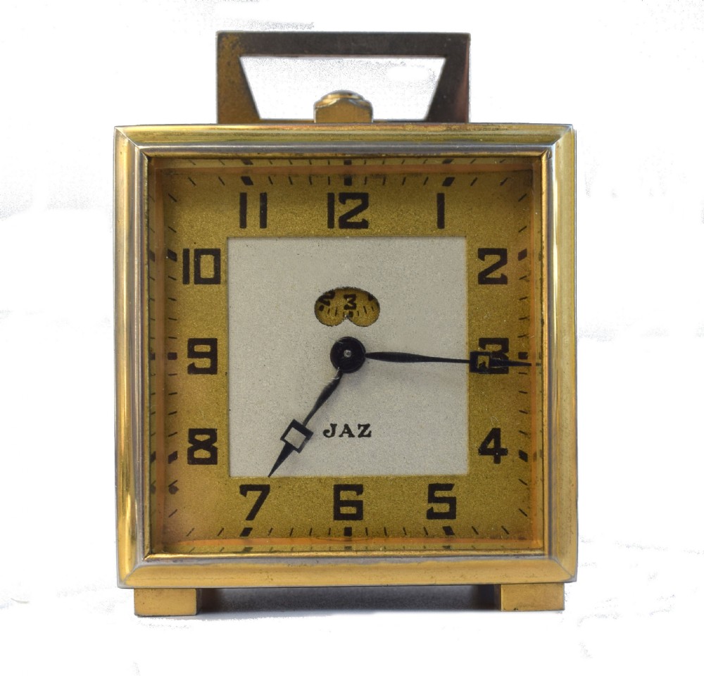 A square French Art Deco miniature alarm clock with a gilded brass casing and two-tone cream dial.