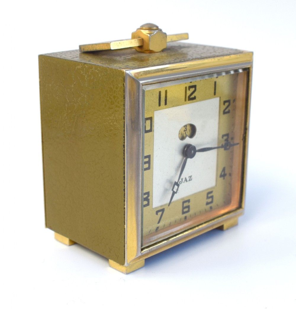A square French Art Deco miniature alarm clock with a gilded brass casing and two-tone cream dial. View IV
