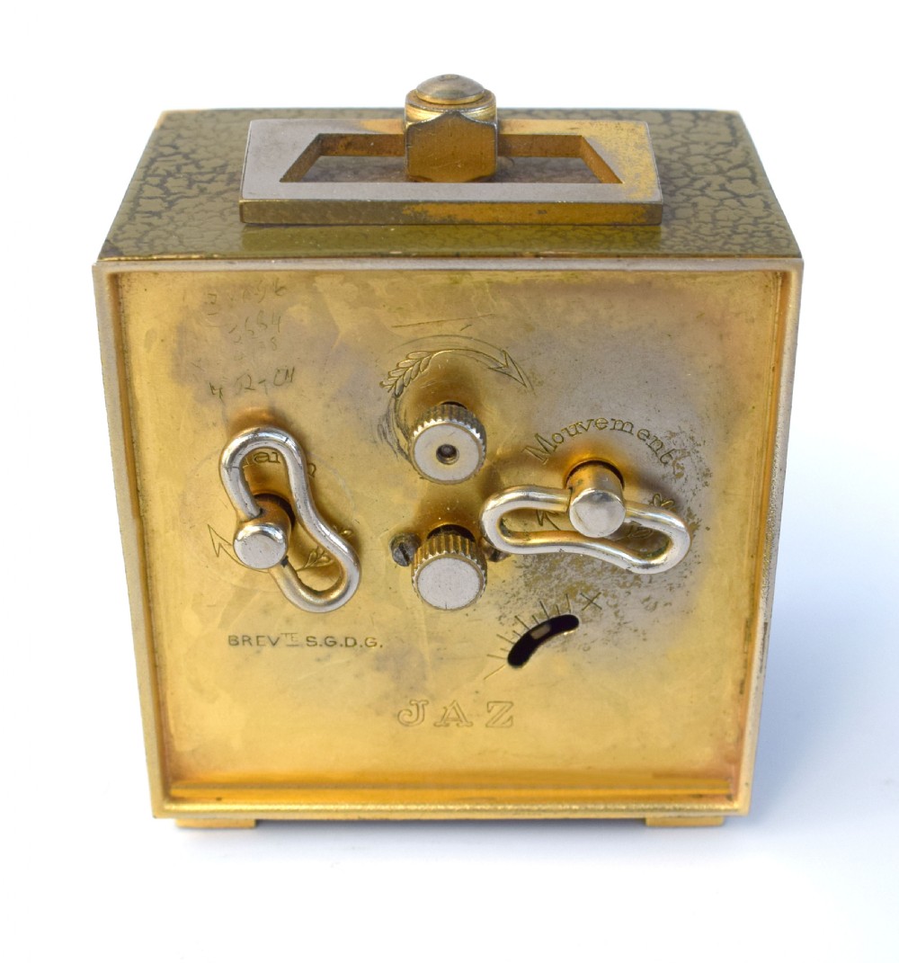 A square French Art Deco miniature alarm clock with a gilded brass casing and two-tone cream dial. View VII