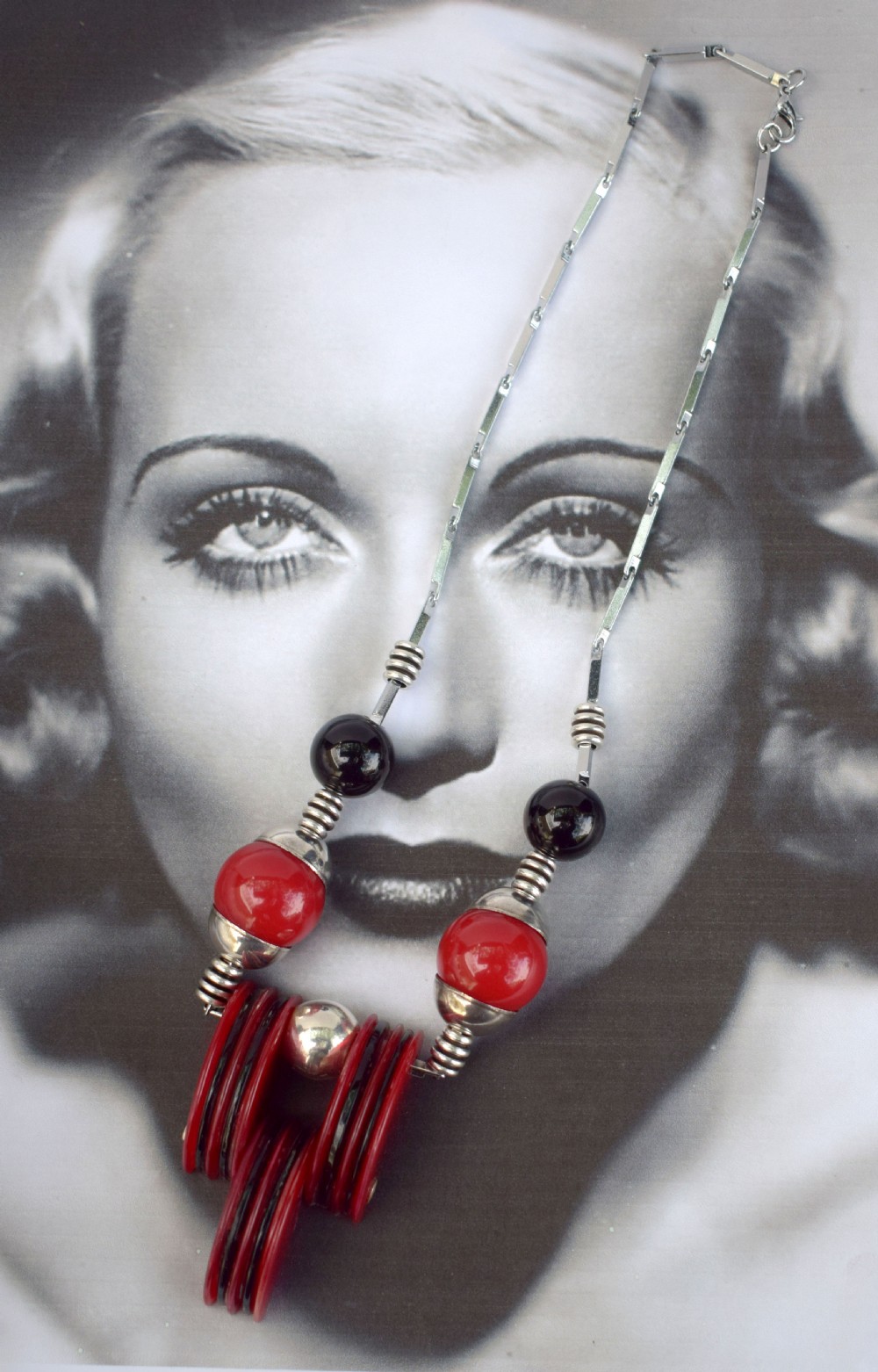 An Art Deco modernist necklace featuring red and black spherical beads, coiled silver-toned metal spacers, and a geometric central pendant composed of stacked red and black discs on a metal link chain. View II