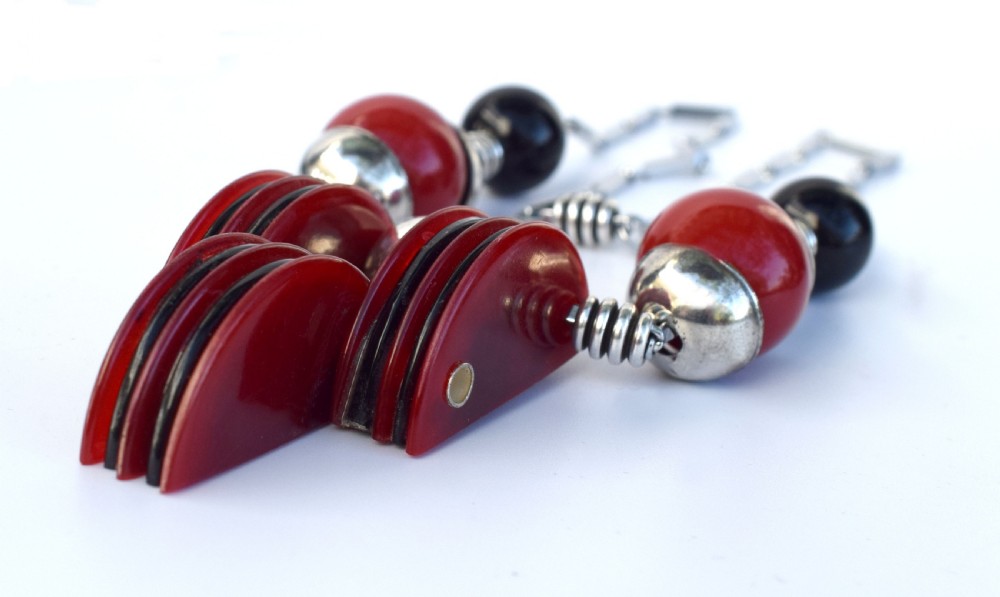 An Art Deco modernist necklace featuring red and black spherical beads, coiled silver-toned metal spacers, and a geometric central pendant composed of stacked red and black discs on a metal link chain. View V