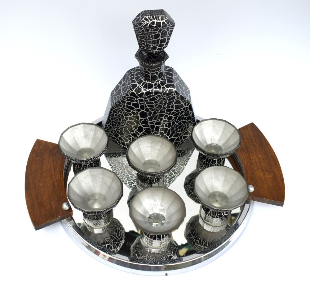 An Art Deco black and silver crackle-patterned glass decanter with six matching small cups arranged on a circular mirrored tray with wood handles. View IV