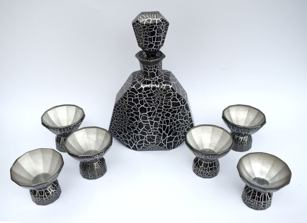 An Art Deco black and silver crackle-patterned glass decanter with six matching small cups arranged on a circular mirrored tray with wood handles. View VII