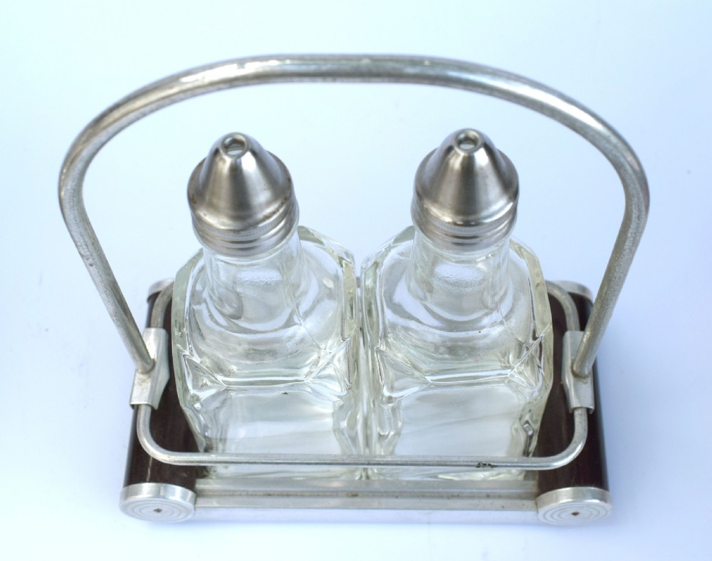 A pair of clear glass oil and vinegar bottles with silver metal tops marked V and O, housed in an Art Deco chrome carrying caddy. View IV