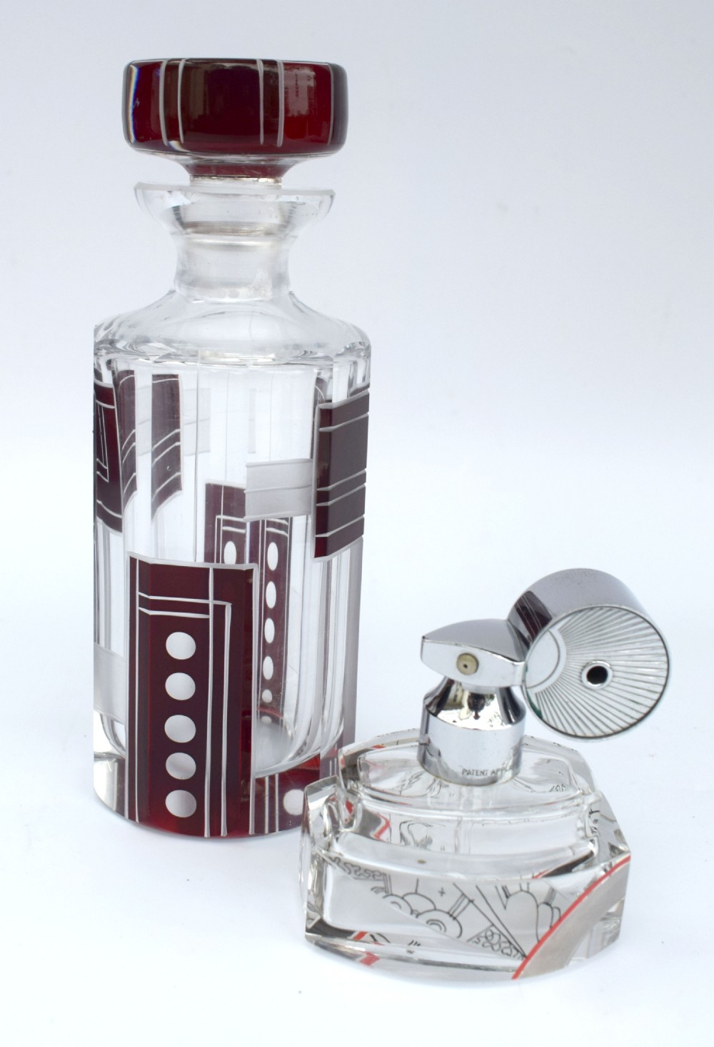 An Art Deco clear glass perfume bottle featuring geometric ruby red cut-to-clear overlay patterns and a matching round glass stopper. View III