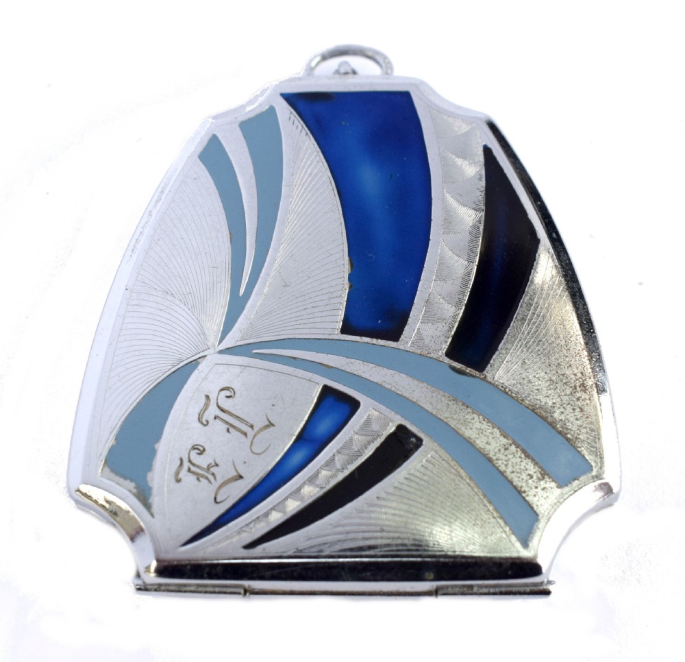 An Art Deco fan-shaped chrome powder compact with geometric blue, light blue, and black enamel panels and engine-turned metal details.