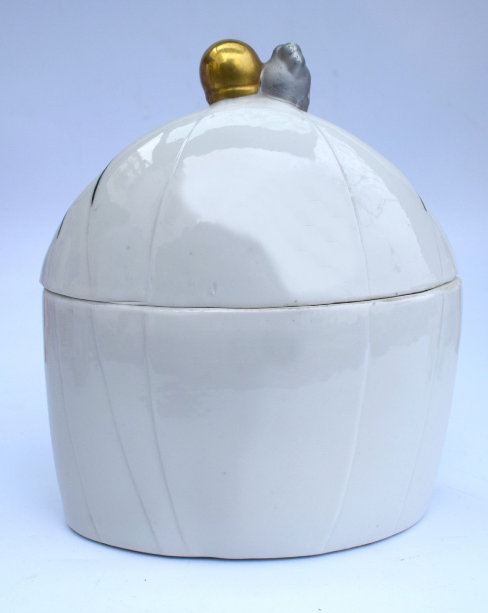 An Art Deco porcelain powder box featuring a lid sculpted in the form of an embracing couple in 1930s evening dress with black, red, and gold accents. View VIII